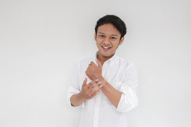 Asian handsome young man applying cream at his hand with smiley face Skin care concept isolated on white background