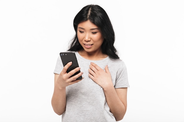 Asian felice bella giovane donna in posa isolato sul muro bianco utilizzando il telefono cellulare.