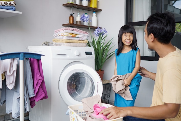 Asian Happy family man father householder and child daughter in laundry with washing machine together