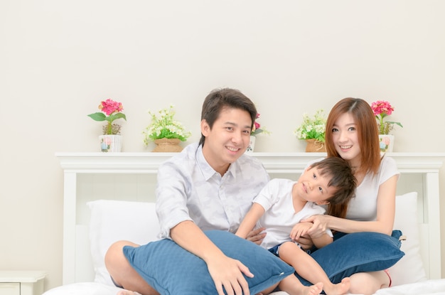 Asian happy family on white bed in the bedroom