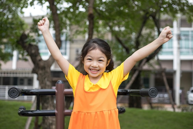 Asian happy girl with orange dress is playing in the playground