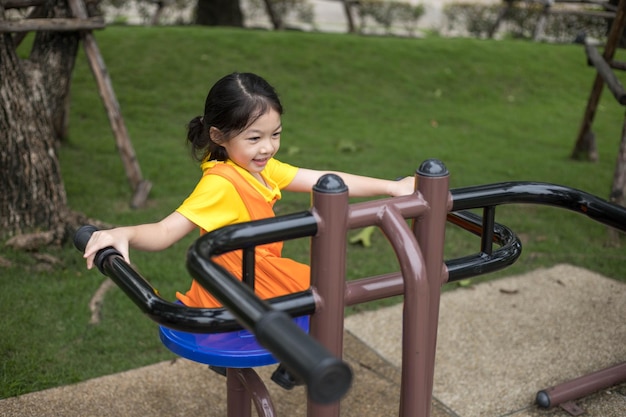 Asian happy girl with orange dress is playing in the playground