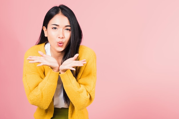 Asian happy portrait beautiful cute young woman teen standing blowing kiss air something on palm hands expresses her love looking to camera studio shot isolated on pink background with copy space