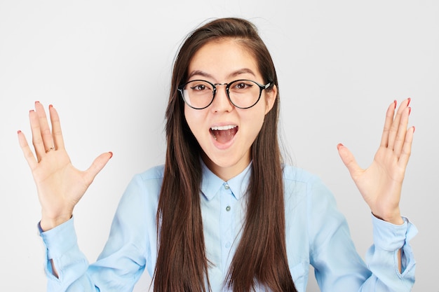 Asian happy student girl in glasses joyfully screams and throws up hands