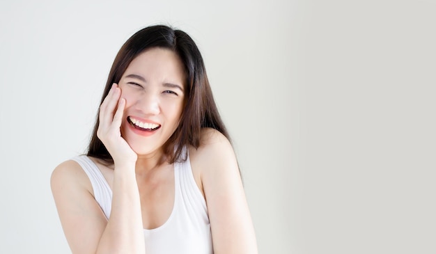 Asian happy woman wear white t-shirt touch her cheek are laugh and smiling with positive thinking and attitude. A Health life concept.