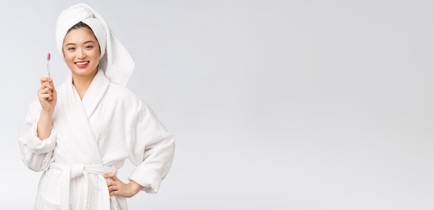 Asian happy woman with toothbrush in bathrobe morning mood