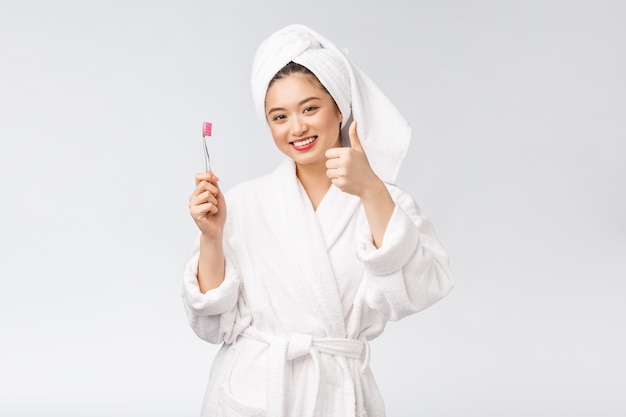 Asian happy woman with toothbrush in bathrobe morning mood.