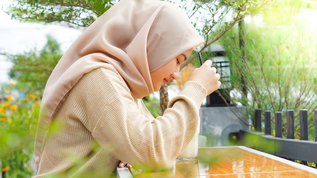 Asian hijab woman drinking at cafe