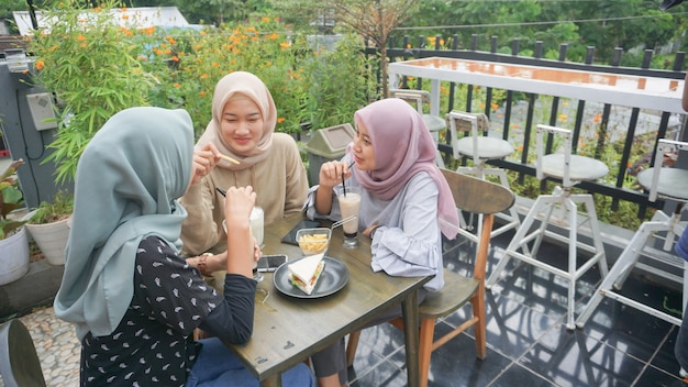 Азиатская группа женщин в хиджабе улыбается в кафе с другом