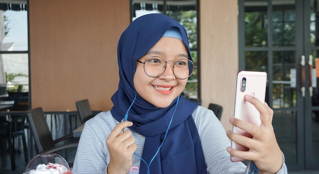 Asian hijab woman listens to music using a headset