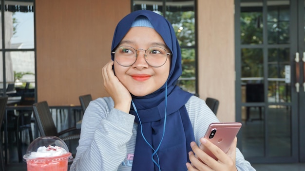 Asian hijab woman listens to music using a headset