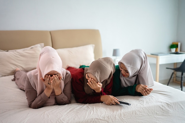 Asian hijab woman with friends cover face because of fear when watching horor film