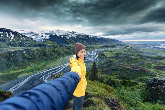 Asian hiker woman holding hands with couple looking the view on top of mountain at Valahnukur viewpoint