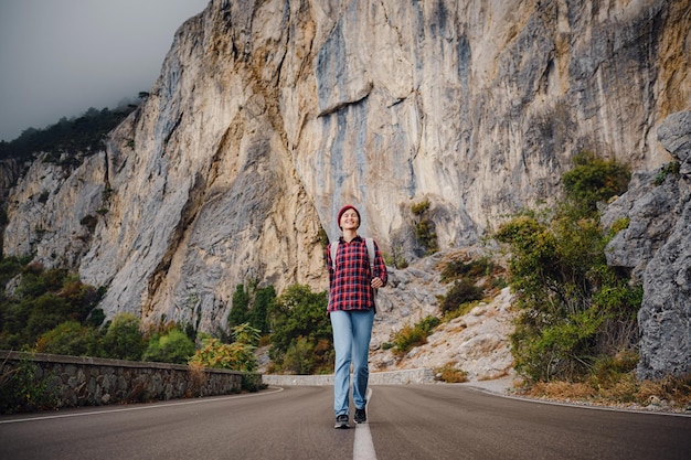 Asian hipster woman walking alone on a mountain highway on an autumn foggy day