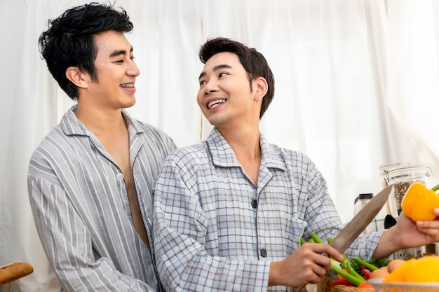 Asian homosexual couple happy and funny cooking salad at kitchen