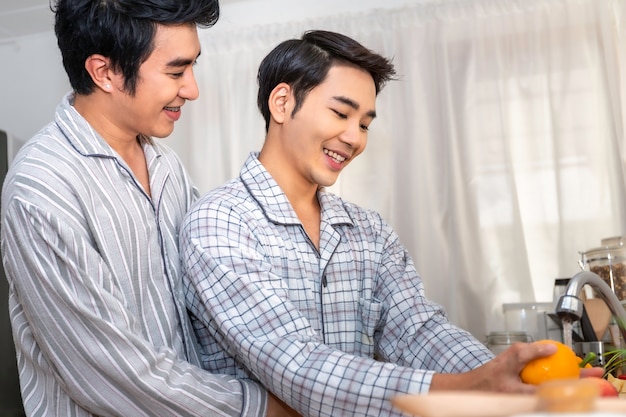 Asian homosexual couple happy and funny cooking salad at kitchen