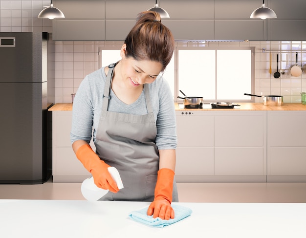 Asian housekeeper cleaning on table with kitchen background