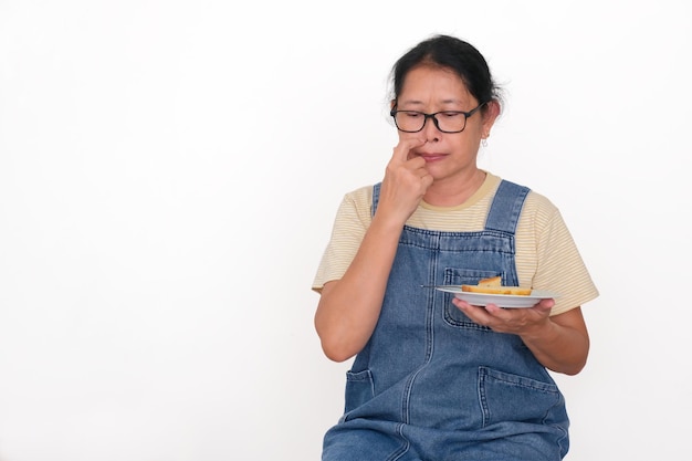 Photo asian housewife sitting alone holding sandwich on a plate losing appetite for breakfast