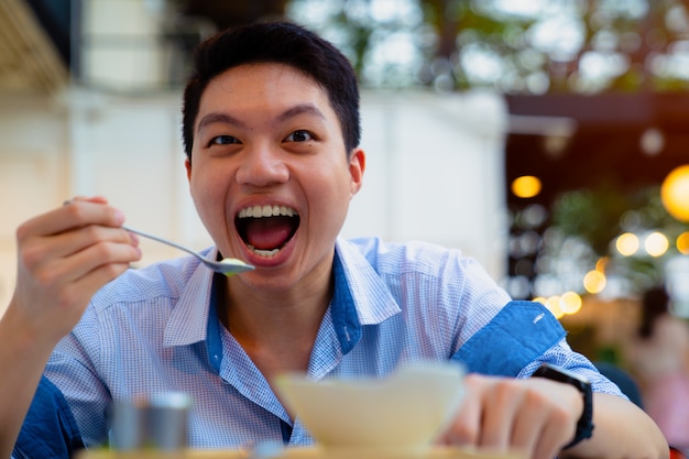 Foto cereale mangiatore di uomini affamato asiatico per la prima colazione che esamina macchina fotografica.