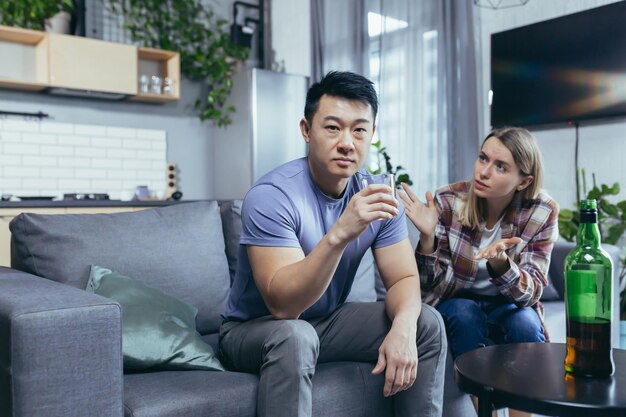 아시아인 남편은 집에서 독한 술을 마시고 아내와 다투고 가정 갈등에서 다인종 가족을 방해하려고 한다