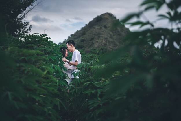 Asian husband kissing his pregnant wife with his eyes closed in mountain. Asian Married couple and family concept.