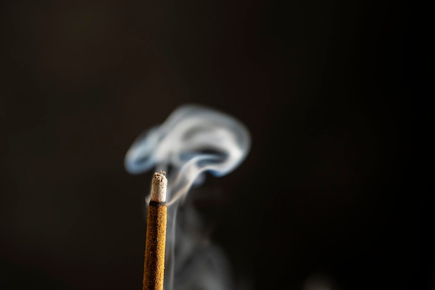 Asian incense stick burning with smoke close up macro