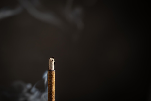 Asian incense stick burning with smoke close up macro