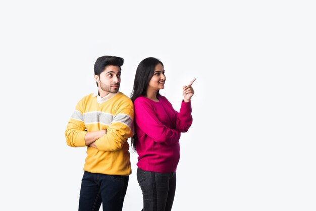 Asian Indian couple wears colourful warm sweater or woolen winter cloths, standing isolated against white background