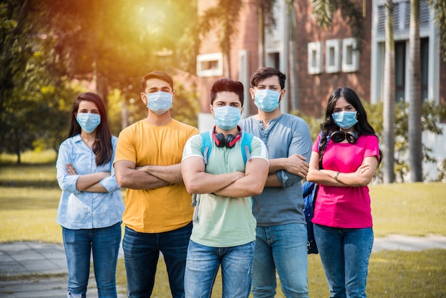 Photo asian indian students wears face mask and follow social distancing norms in college or university campus after corona pandemic unlock, focus on one student