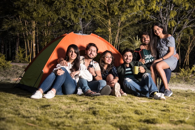 Asian Indian young friends have good time on camping trip, relaxing vacation with fun outside tents