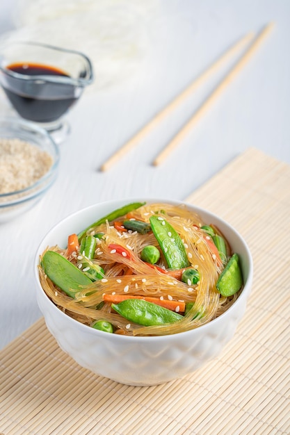 Insalata asiatica di japchae di pasta di vetro saltata in padella e verdure servite con salsa di soia sul tavolo bianco