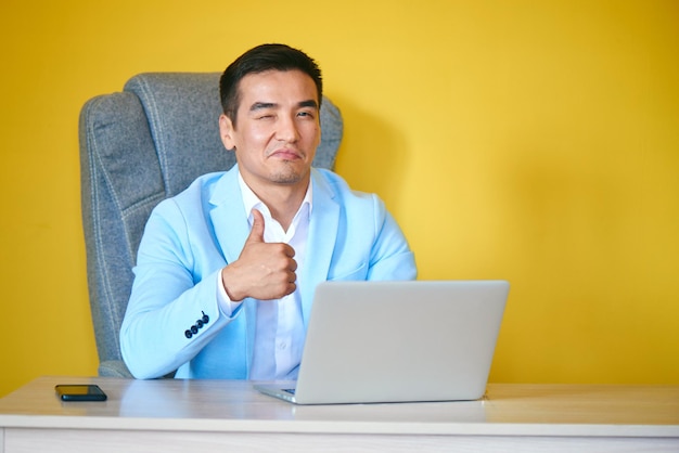 Asian Kazakh businessman in a suit and glasses with a laptop computer works in the office, a successful professional manager solves business issues