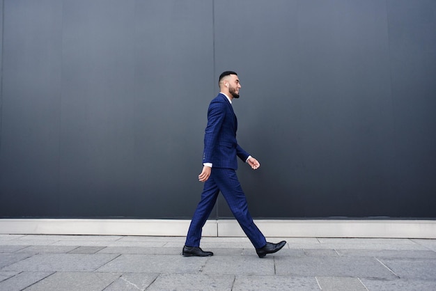 Photo asian kazakh businessman walks along the black wall