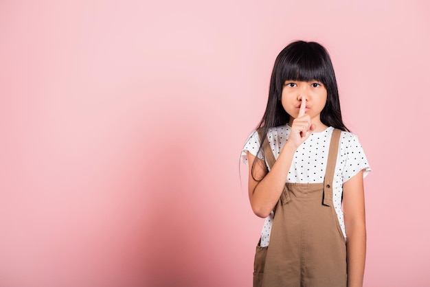 Asian kid 10 years old holding finger on lips symbol of hush gesture of asking quiet