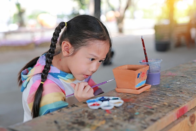 Asian kid girl paint on earthenware dish