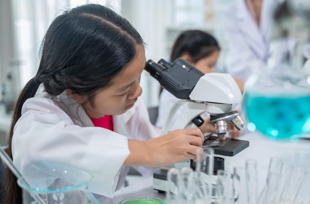 Foto bambino asiatico che impara con lo scienziato in laboratorio. esame fisico e classe di educazione scientifica.