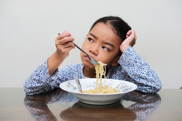 Asian kid showing no appetite expression when try to eat noodles