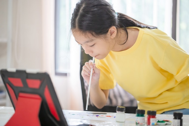 아시아 어린이 온라인 학습 수업 연구, 놀이방 탁자에서 어린이 그림 그리기, 소녀는 집에서 온라인으로 창의적인 과정 예술 그림을 배웁니다.