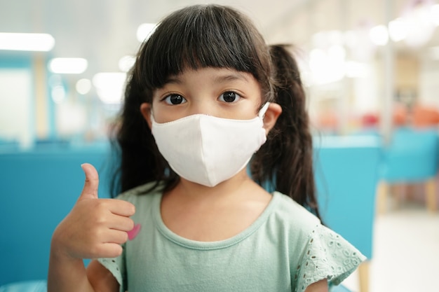 Asian kid use medical mask with thumb up