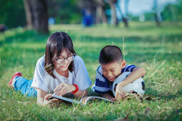 asian kids reading book in the park