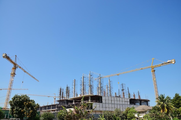 아시아 노동자와 태국 노동 노동자는 태국 방콕의 수도 건설 현장에서 기계 및 중장비 작업 건축업자 새로운 구조 타워 고층 건물을 사용합니다.