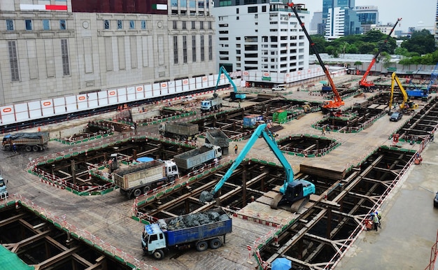 アジアの労働者とタイの労働者は、タイのバンコクの首都の建設現場で足場に機械と重機作業ビルダーの新しい構造タワー高層ビルを使用します