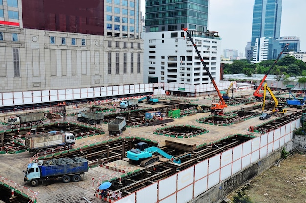 アジアの労働者とタイの労働者は、タイのバンコクの首都の建設現場で足場に機械と重機作業ビルダーの新しい構造タワー高層ビルを使用します