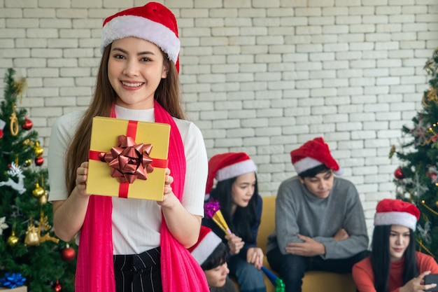 Asian lady in beautiful dress with a gift box. cute smiling. having fun christmas party. christmas eve