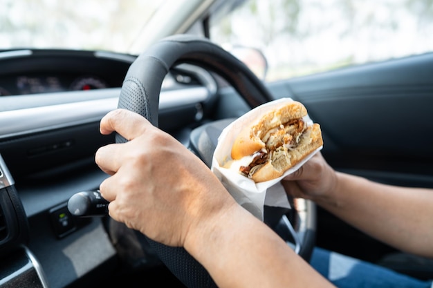 ハンバーガーを車で食べるアジア人女性が危険で事故を起こす