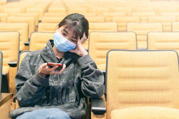 Asian lady protecting herself from virus by wearing protective face mask using smartphone.