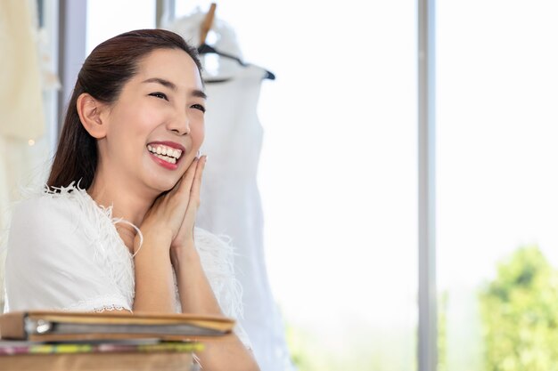 Asian lady smiling pretty choosing dress in a wedding shop.