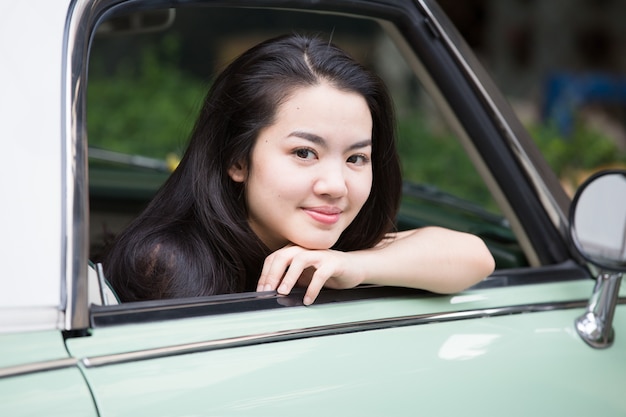 Asian lady smiling in a vintage car