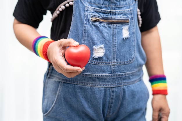 Азиатские дамы, носящие браслеты с радужным флагом и держащие красное сердце, символ месяца гордости ЛГБТ, ежегодно отмечают в июне социальные мероприятия геев, лесбиянок, бисексуалов, транссексуалов и прав человека.