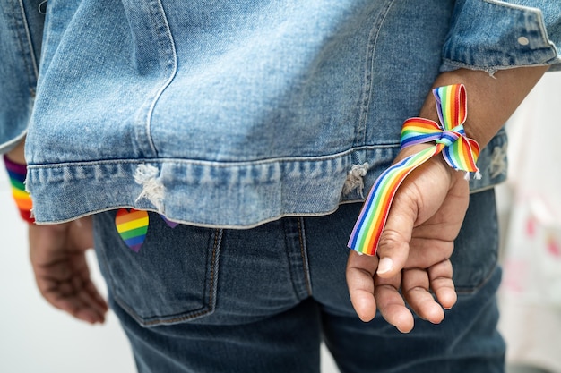 Фото Азиатская дама в браслетах с радужным флагом, символ месяца гордости лгбт, отмечает ежегодный июньский праздник прав человека геев, лесбиянок, бисексуалов, трансгендеров
